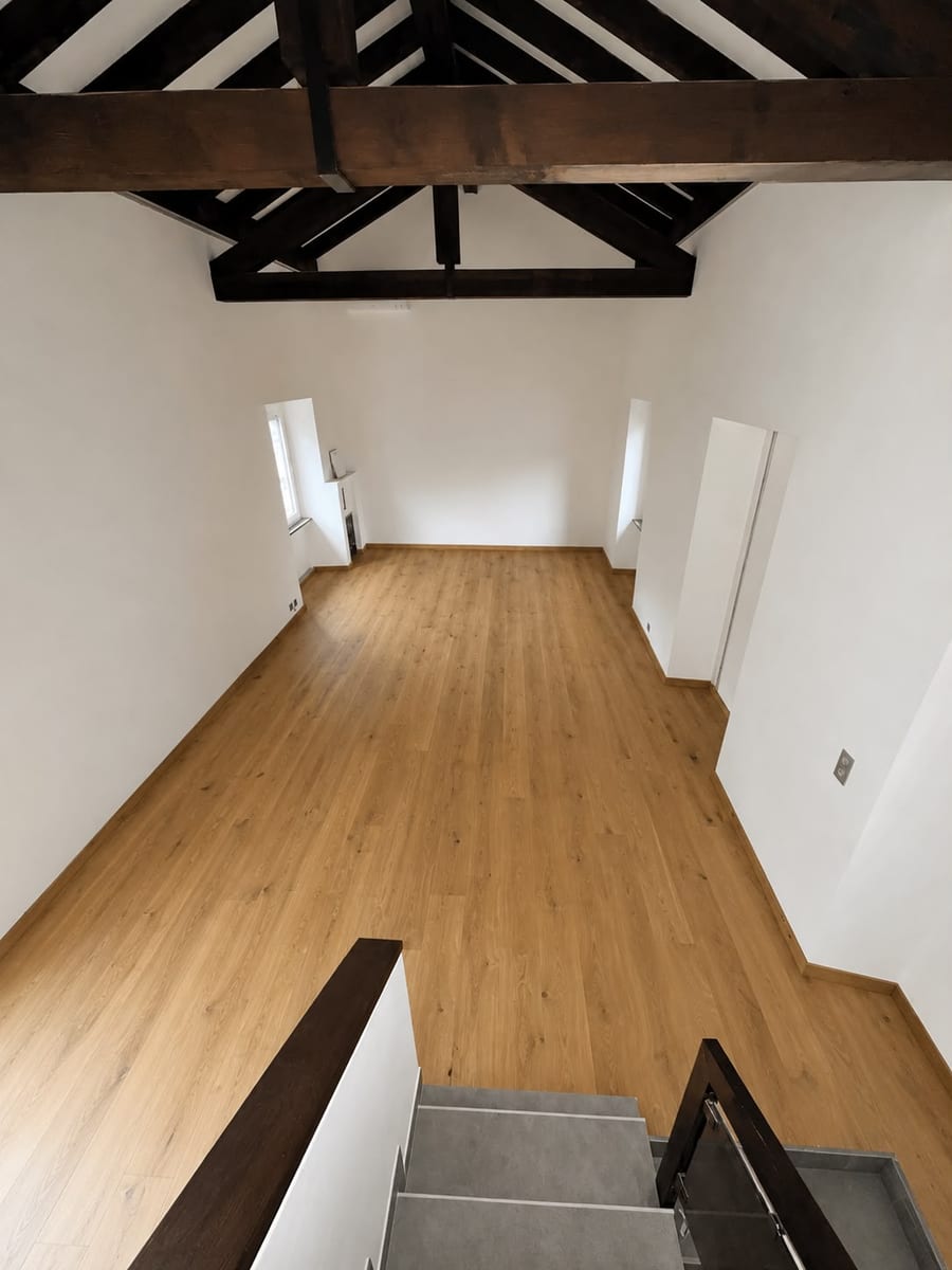 Dopo — posa del riscaldamento a pavimento e del parquet in un sottotetto con travi a vista, in Ticino