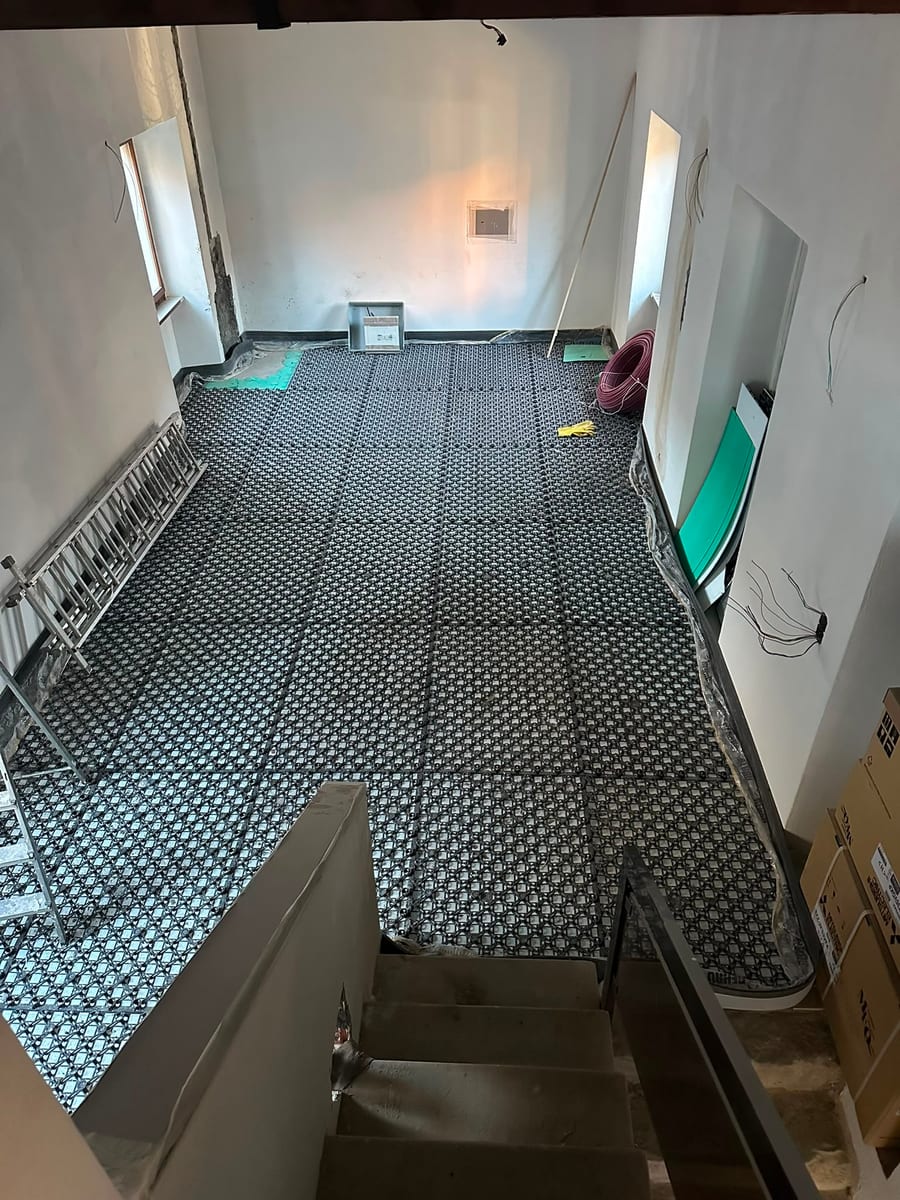 Prima — posa del riscaldamento a pavimento e del parquet in un sottotetto con travi a vista, in Ticino